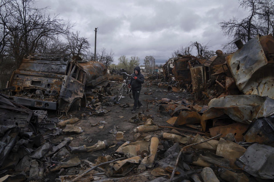 FILE - A man carries bicycle along a street filled with destroyed Russian military vehicles near Chernihiv, Ukraine, Sunday, April 17, 2022. With Russia’s military failings in Ukraine mounting, no country is paying closer attention than China to how a smaller, outgunned force has badly bloodied what was thought to be one of the world’s strongest armies. (AP Photo/Evgeniy Maloletka, File)