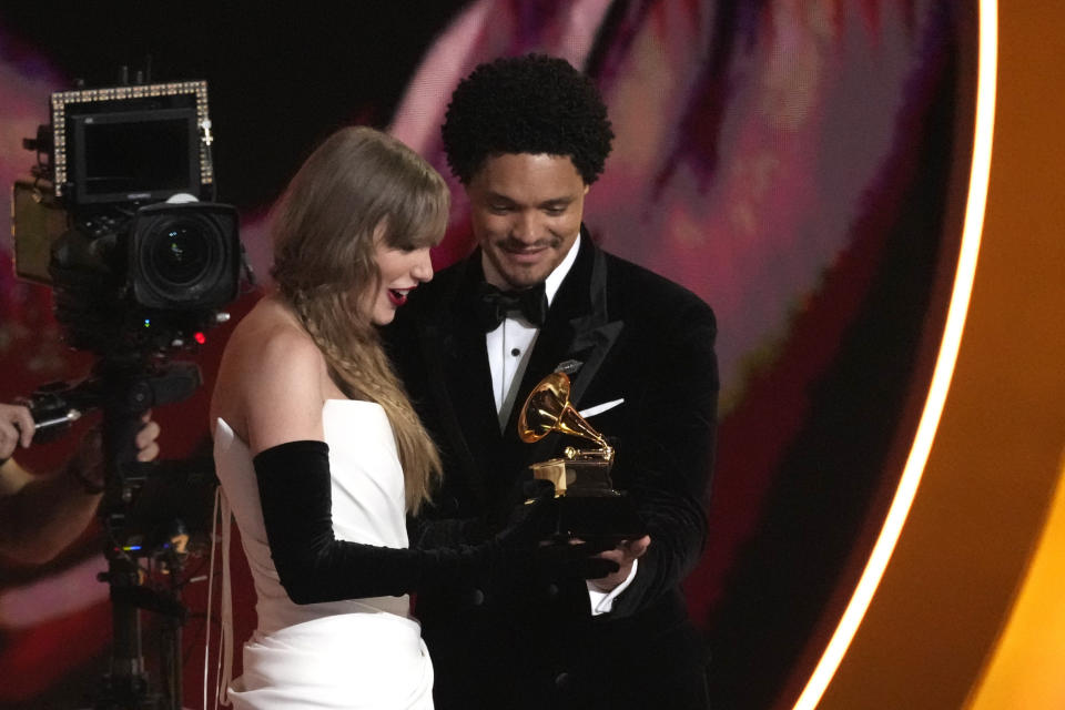 El maestro de ceremonias Trevor Noah, derecha, le entrega el premio a mejor álbum pop vocal para Taylor Swift por "Midnights" en la 66a entrega anual del Grammy el domingo 4 de febrero de 2024 en Los Ángeles. (Foto AP/Chris Pizzello)