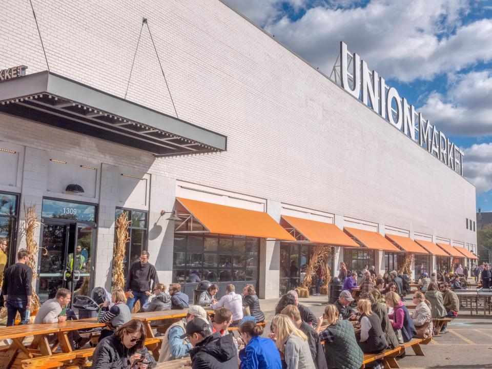 union market in DC, large white building with white bricks, orange awnings outside with people eating