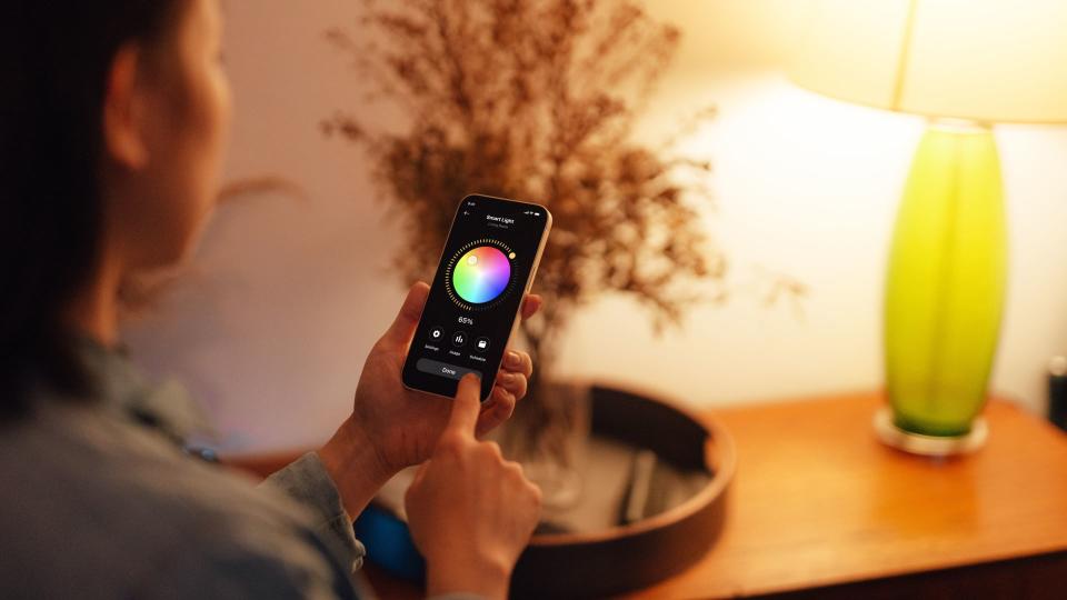 A person using an app to adjust the settings on a smart bulb