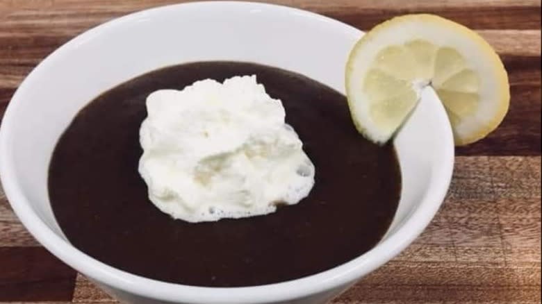 Brown soup with whipped cream and lemon slice