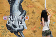 <p>Mary Beth Nickerson signs the wall outside of Pulse Nightclub while visiting the memorial on the one year anniversary of the shooting in Orlando, Florida June 12, 2017. (REUTERS/Scott Audette) </p>