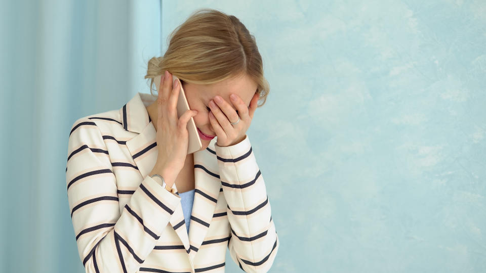 Young alarmed woman in a striped jacket talking on the phone.