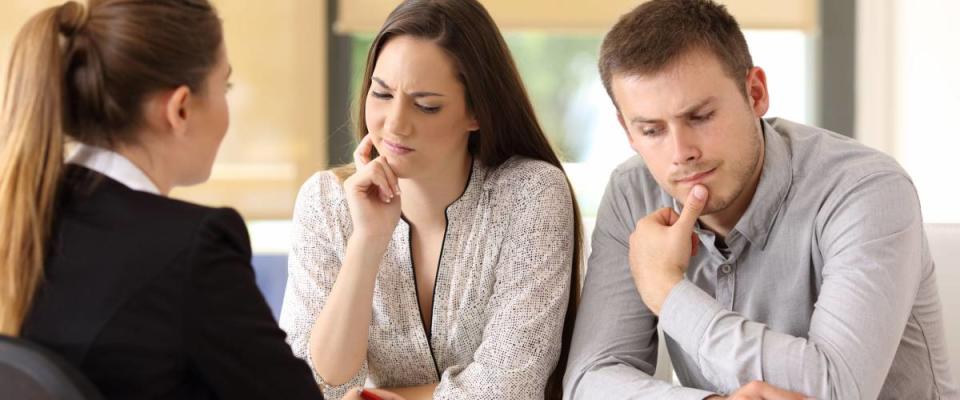 Office worker attending and showing contract trying to convince to a suspicious couple sitting in a desk at office