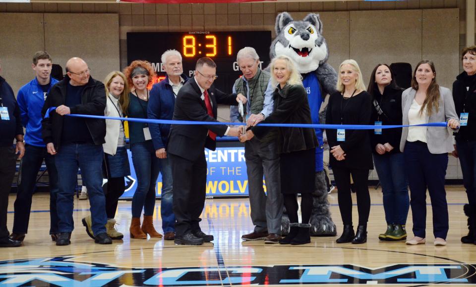 North Central Michigan College president David Roland Finley and Petoskey Plastics' Paul and Melissa Keiswetter (middle) get set to cut the ribbon at Petoskey Plastics Arena in November in a court dedication during the first-ever men's and women's college basketball games at the college.