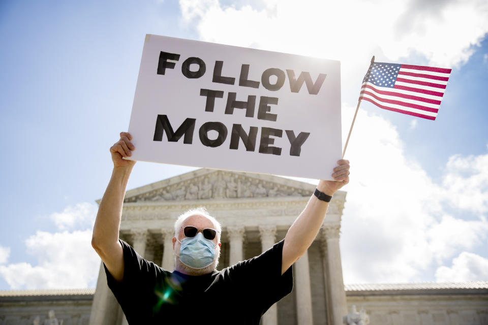 Bill Christeson holds up a sign that reads "Follow the Money" outside the Supreme Court, Thursday, July 9, 2020, in Washington. The Supreme Court ruled Thursday that the Manhattan district attorney can obtain Trump tax returns while not allowing Congress to get Trump tax and financial records, for now, returning the case to lower courts. (AP Photo/Andrew Harnik)