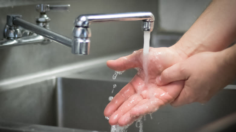 man scrubbing hands in kitchen 