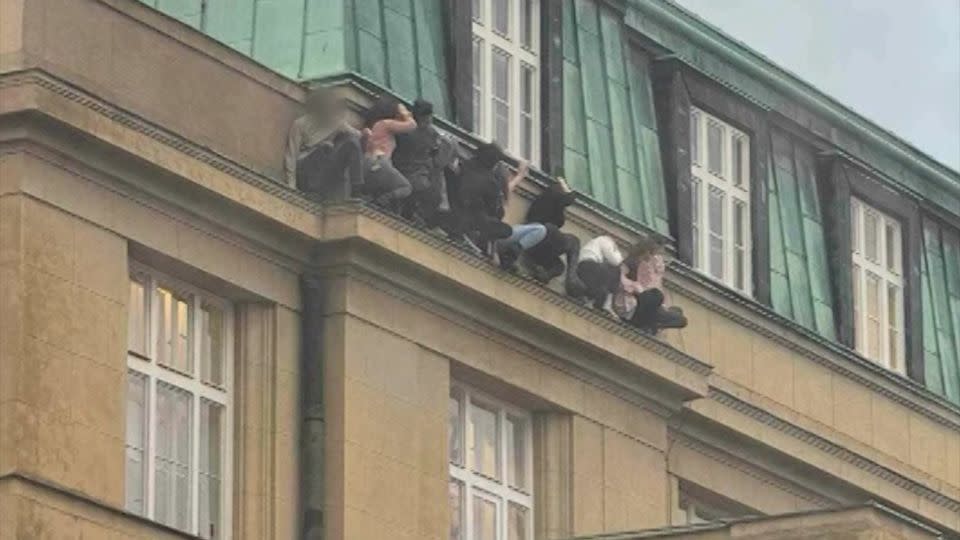 Students are seen hiding on a ledge at Charles University. - From @elirozic/X