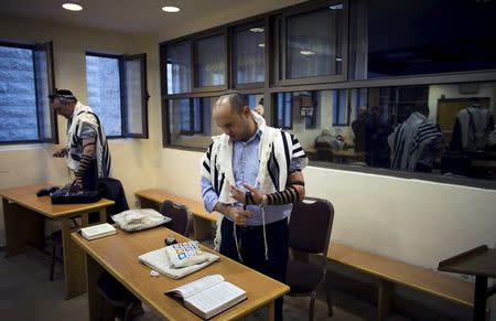 Israel's Economy Minister Naftali Bennett, head of the far-right Jewish Home party, prays at a synagogue in Jerusalem where two Palestinian militants killed four rabbis and a policeman, in this November 19, 2014 file photo. REUTERS/Ronen Zvulun/Files