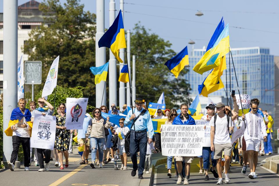 People carry Ukrainian national flags and placards during a march to mark Ukraine's Independence Day in Geneva, Switzerland (EPA)