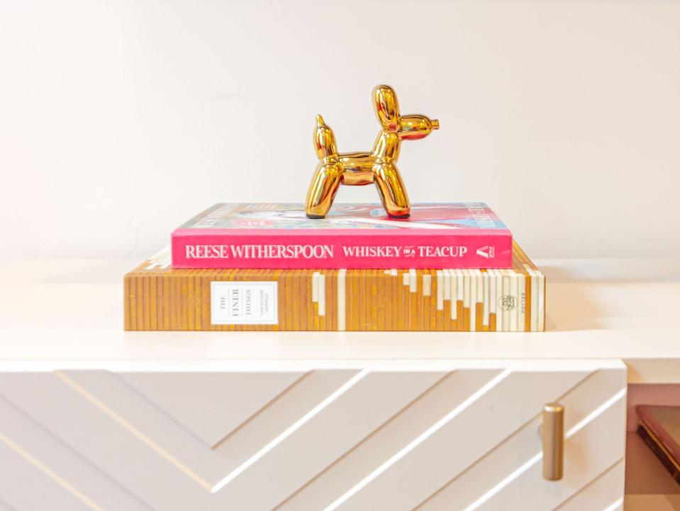 A statue of a gold wiener dog sits on a stack of books.