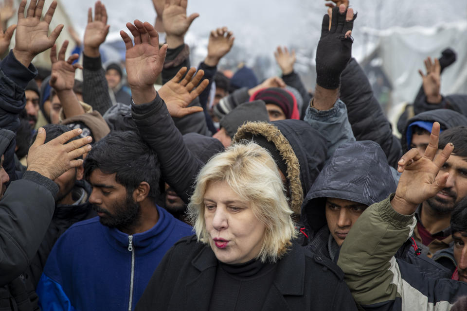 Surrounded by migrants, Dunja Mijatovic, the Council of Europe Commissioner for Human Rights addresses the media at the Vucjak refugee camp outside Bihac, northwestern Bosnia, Tuesday, Dec. 3, 2019. Mijatovic has demanded immediate closure of the migrant camp where hundreds of people have started refusing food and water to protest dismal living conditions as wintry weather sets in. (AP Photo/Darko Bandic)