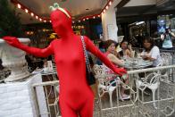 Diners look at a participant wearing Zentai costume, or skin-tight bodysuit from head to toe, during a march down the shopping district of Orchard Road as part of the Zentai Art Festival in Singapore May 23, 2015. Close to 50 participants strutted down the busy shopping district during the Zentai art festival which is jointly organized by the Japanese embassy. The festival includes performances and discussions on Zentai from May 22 to from June 5. REUTERS/Edgar Su TPX IMAGES OF THE DAY