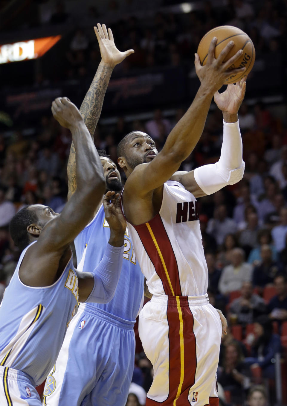 Miami Heat guard Dwyane Wade (3) prepares to shoot against Denver Nuggets forward Wilson Chandler (21) and J.J. Hickson, left, during the first half of an NBA basketball game in Miami, Friday, March 14, 2014. (AP Photo/Alan Diaz)