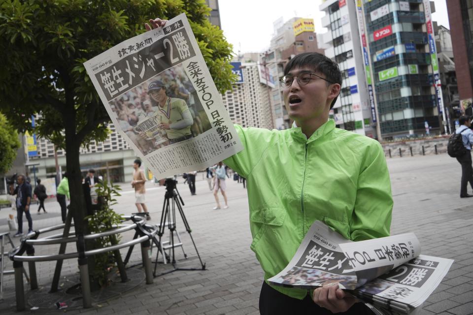 A staff distributes an extra edition of the Yomiuri Shimbun newspaper reporting on Japanese golfer Yuka Saso winning the U.S. Women's Open golf tournament Monday, June 3, 2024, in Tokyo. The Japanese title reads as "Saso won second major." (AP Photo/Eugene Hoshiko)