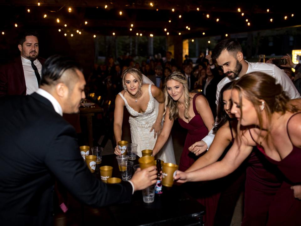 The bride and guests playing a drinking game at campground wedding