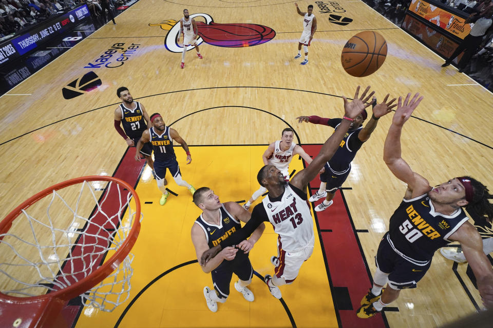 Miami Heat center Bam Adebayo (13) and Denver Nuggets forward Aaron Gordon (50) reach for the ball during the second half in Game 4 of the basketball NBA Finals, Friday, June 9, 2023, in Miami. (Kyle Terada/Pool Photo via AP)