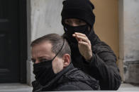 A plain clothed policeman escorts handcuffed actor and director Dimitris Lignadis, as he leaves a magistrate's office in Athens, Sunday, Feb. 21, 2021. Lignadis appeared at a court hearing on Sunday and was given until Wednesday to respond to charges of multiple rapes by an examining magistrate. Court authorities said he will remain jailed until then. According to court sources, Lignadis is accused of rape by two men who were minors when the events occurred in 2010 and 2015. (AP Photo/Yorgos Karahalis)