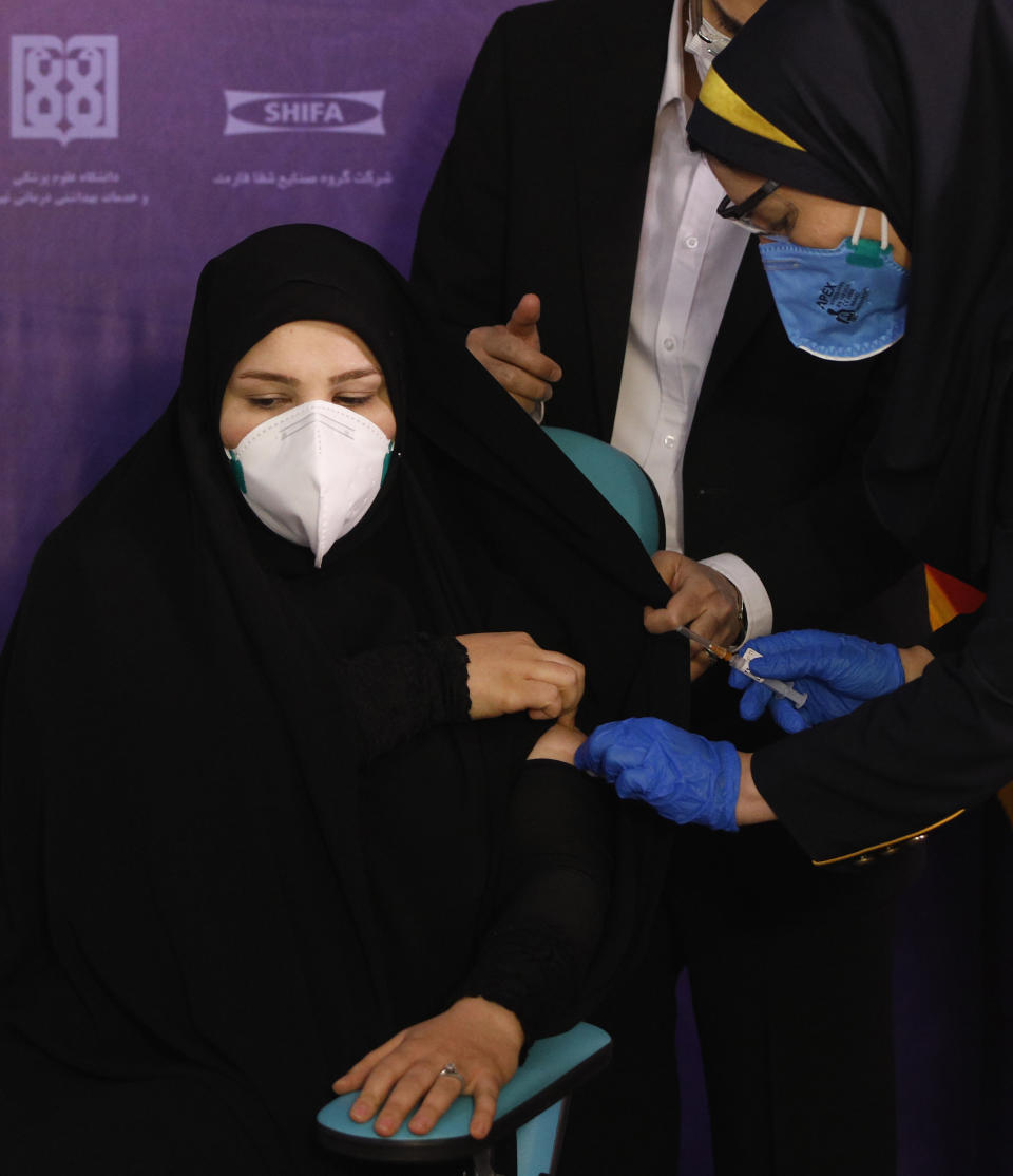 Tayebeh Mokhber is injected with the Coviran coronavirus vaccine produced by Shifa Pharmed, part of a state-owned pharmaceutical conglomerate, in a ceremony in Tehran, Iran, Tuesday, Dec. 29, 2020. The first study of the safety and effectiveness of the coronavirus vaccine in Iran began Tuesday, state TV reported, with dozens due to receive the domestically developed shot in the hardest-hit country in the Middle East. (AP Photo/Aref Taherkenareh)