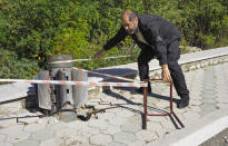 A man fences off a tail of a multiple rocket after shelling by Azerbaijan's artillery during a military conflict in Shushi, outside Stepanakert, the separatist region of Nagorno-Karabakh, Sunday, Oct. 18, 2020. The latest outburst of fighting between Azerbaijani and Armenian forces began Sept. 27 and marked the biggest escalation of the decades-old conflict over Nagorno-Karabakh. The region lies in Azerbaijan but has been under control of ethnic Armenian forces backed by Armenia since the end of a separatist war in 1994. (AP Photo)