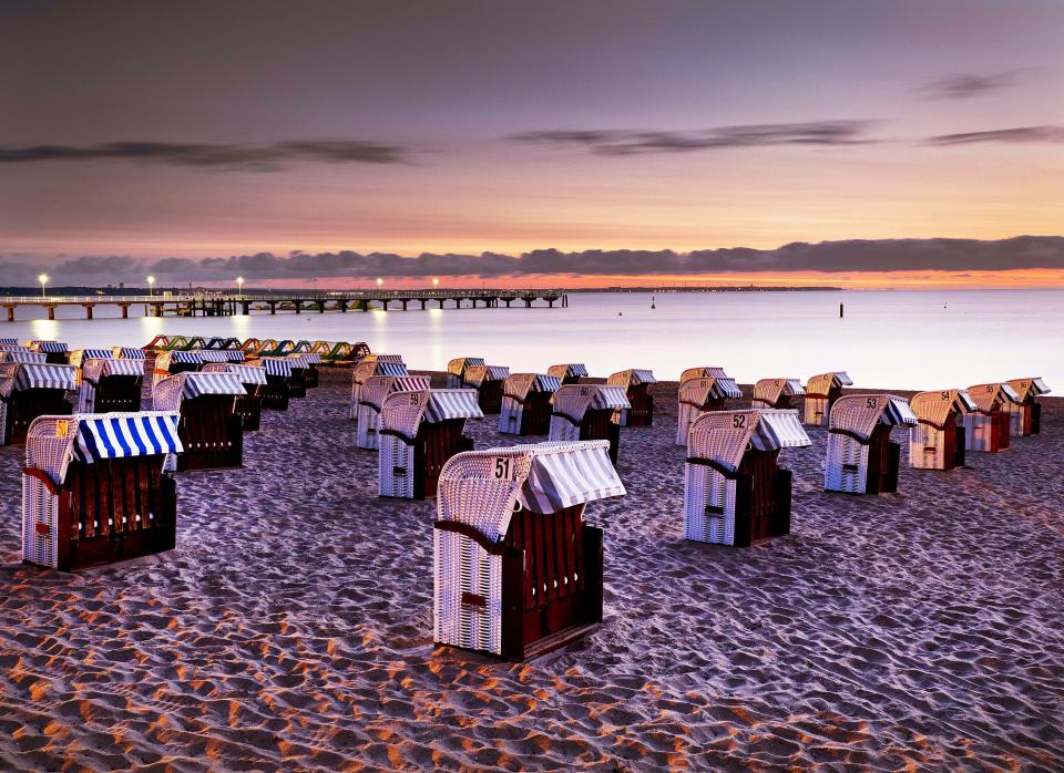 FILE-In this Aug. 21, 2018 file photo beach chairs are lined up before sunrise in Timmendorfer Strand at the Baltic Sea, northern Germany, Tuesday, Aug. 21, 2018. Scientists say that half of the world's sandy beached are at risk of disappearing by the end of the century if climate changes continues unchecked. Researchers at the European Union's Joint Research Center in Ispra, Italy, used satellite images to track the way beaches changed over the past 30 years and project how global warming might affect them in the future. (AP Photo/Michael Probst)