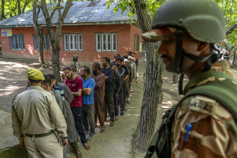 Security forces stand guard near Kashmiri villagers waiting to vote outside a polling booth during the fifth round of multi-phase national election in Beerwah, west of Srinagar, Indian controlled Kashmir, Monday, May 20, 2024. (AP Photo/Dar Yasin)