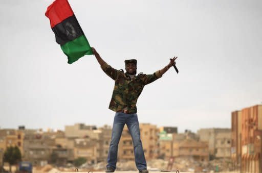 A Libyan rebel fighter holds a knife as he waves the revolution flag in a street of Benghazi. French air raids and US Tomahawk missiles pounded targets in Libya on Saturday, in an international campaign to prevent Moamer Kadhafi from crushing a month-old uprising against his rule