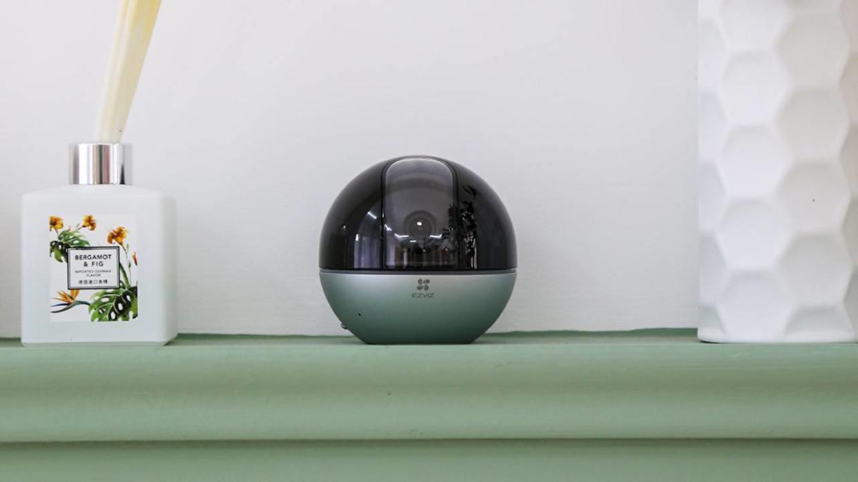  EZVIZ E6 3K camera sitting on a shelf next to a scent diffuser. 