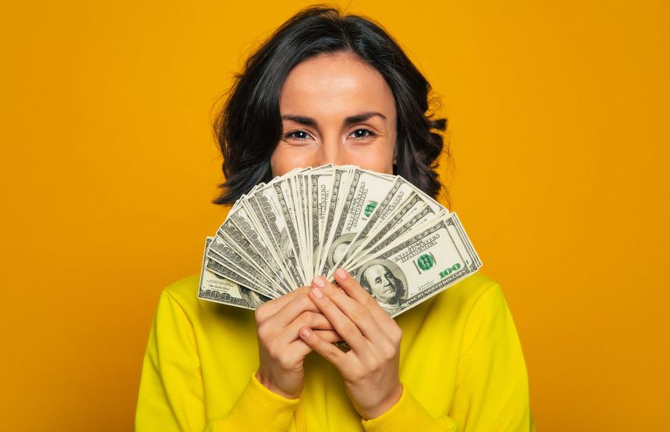 Smiling person holding up a fan of cash. 