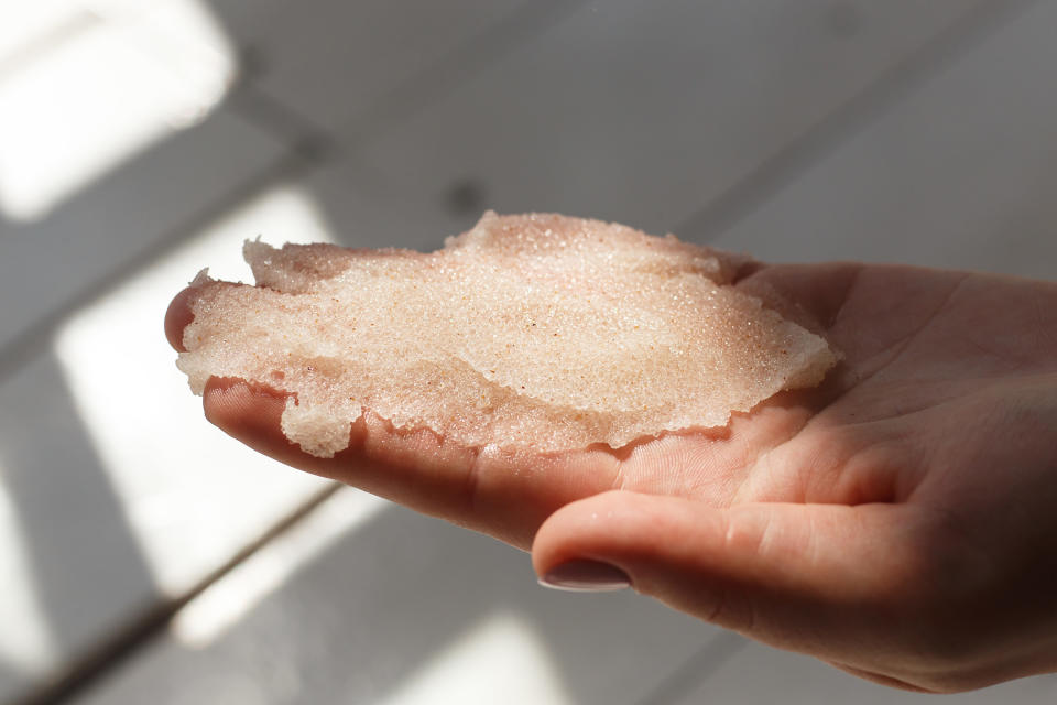 A woman holding a dollop of a scrub in her hand