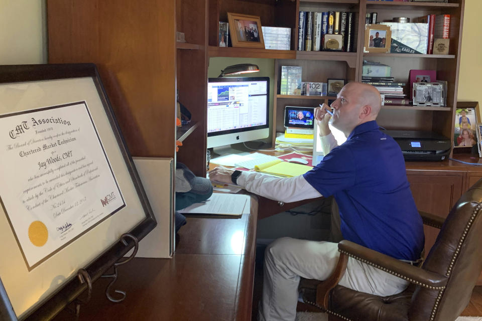 In this image provided by Jay Woods, Woods, a Designated Market Maker with IMC and NYSE Floor Governor, who normally works on the New York Stock Exchange trading floor, works in his home office in Basking Ridge, N.J., Thursday, March 26, 2020. Stocks are opening lower on Wall Street as the market gives back some of the gains it piled up over the past three days. (Shannon Woods/Courtesy Jay Woods via AP)