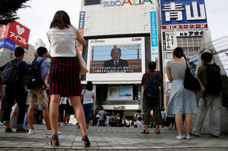 FILE PHOTO: People watch a large screen showing Japanese Emperor Akihito's video address in Tokyo, Japan, August 8, 2016. REUTERS/Kim Kyung-Hoon/File Photo