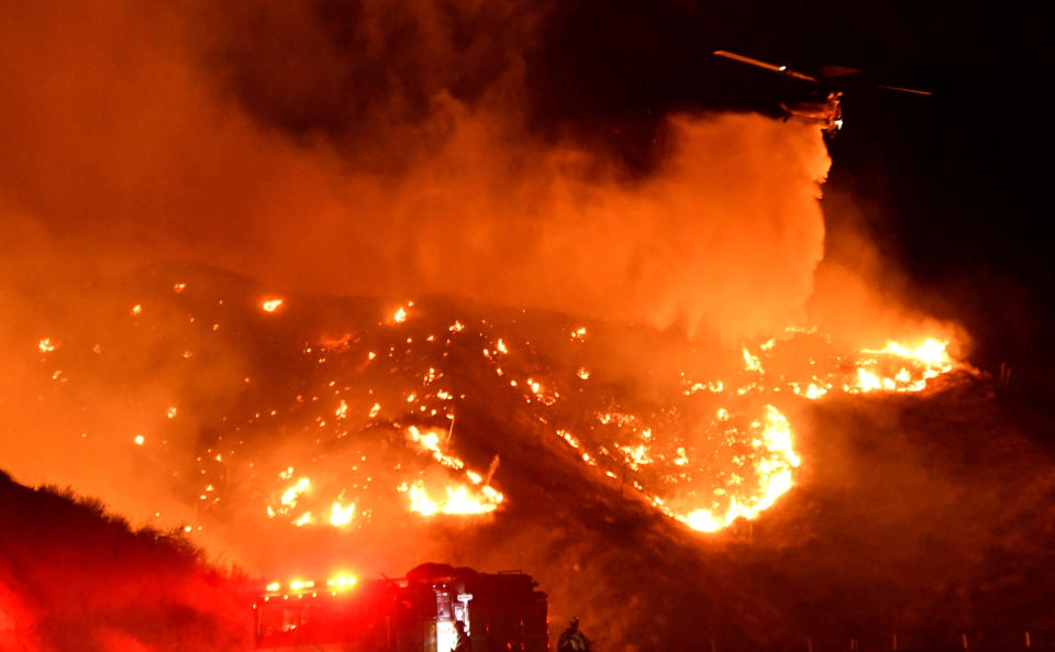 A helicopter makes a water drop, as a wind driven wildfire continues to burn in Canyon Country north of Los Angeles, California, Oct. 25, 2019. (Photo: Gene Blevins/Reuters)