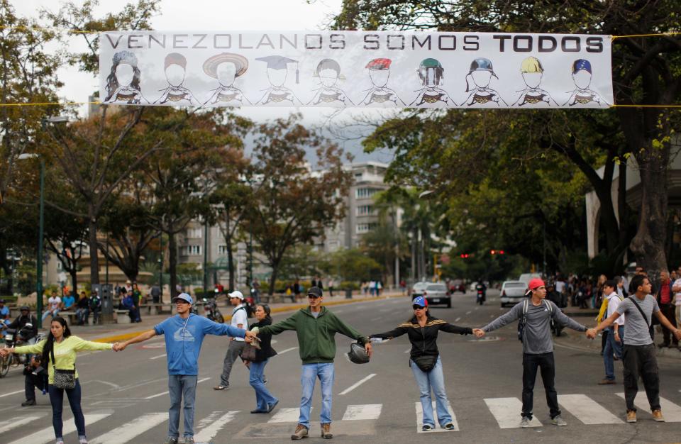 Manifestantes se toman de las manos para bloquear una avenida en el barrio de Altamira en Caracas, Venezuela, el lunes 24 de febrero de 2014. La capital venezolana amaneció el lunes en medio de nuevas tensiones luego de que decenas de manifestantes bloquearon algunas de las principales avenidas en protesta contra el gobierno, en medio de la crisis política que lleva tres semanas y ha dejado 14 muertos y más de un centenar de heridos. (AP foto/Rodrigo Abd)