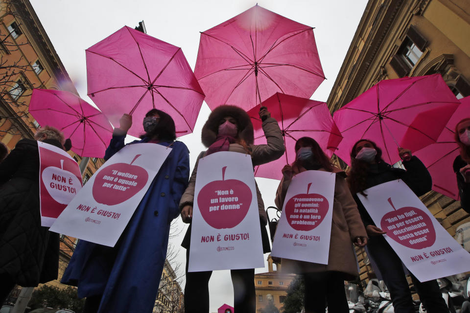 FILE - Women wear signs with writing reading in Italian "Welfare is not the same for all", left, "Its not a woman's job", second from left, "Men advance; childbirth is not their problem," and "I don't have children but to be discriminated its enough to be a woman," right, during a demonstration in front of the Finance Ministry on International Women's Day in Rome, Monday, March 8, 2021. Advocates for women and the LGBTQ community in Italy are worrying that the decisive victory by Giorgia Meloni and her far-right party in Italy's national election which took place Sunday, Sept. 25, 2022, will bring setbacks for civil rights. (AP Photo/Alessandra Tarantino, File )