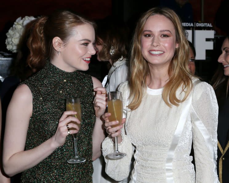 Emma Stone and Brie Larson, in McQueen, get bubbly. (Photo: Getty Images)