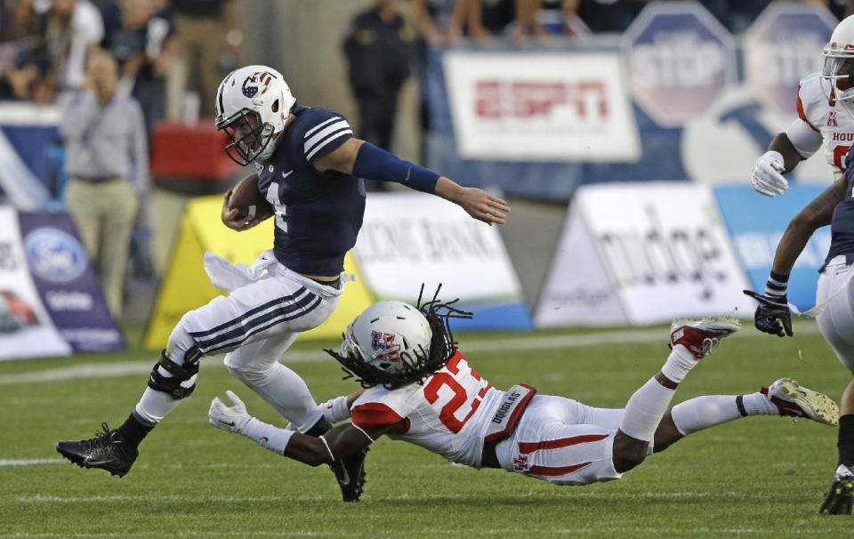 Brigham Young quarterback Taysom Hill (4) out runs the tackle from Houston defensive back Trevon Stewart (23) in the first quarter of an NCAA college football game Thursday, Sept. 11, 2014, in Provo, Utah.(AP Photo/Rick Bowmer)