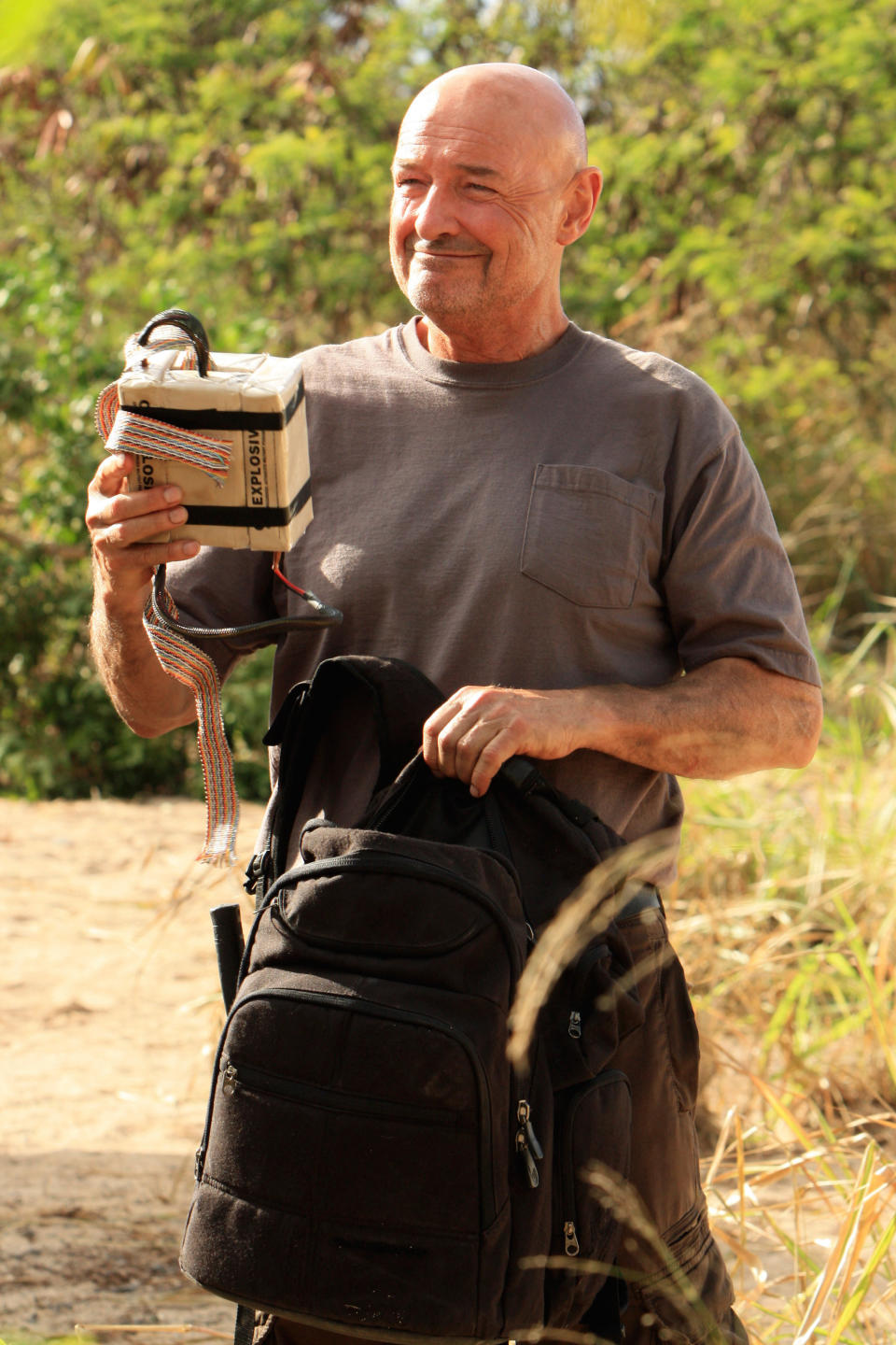 John Locke smiling and pulling explosives out of a bag