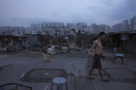 <p>A resident walks outside his illegal rooftop hut, located next to a public housing estate, against the backdrop. of the Hong Kong skyline, May 6, 2017. (Photo: Kin Cheung/AP) </p>