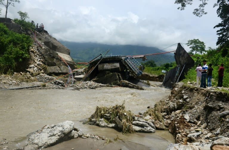 Bystanders look at a damaged bridge in the village of Garidhura, some 35kms from Siliguri in the eastern Indian state of West Bengal on July 1, 2015, after landslides in the region