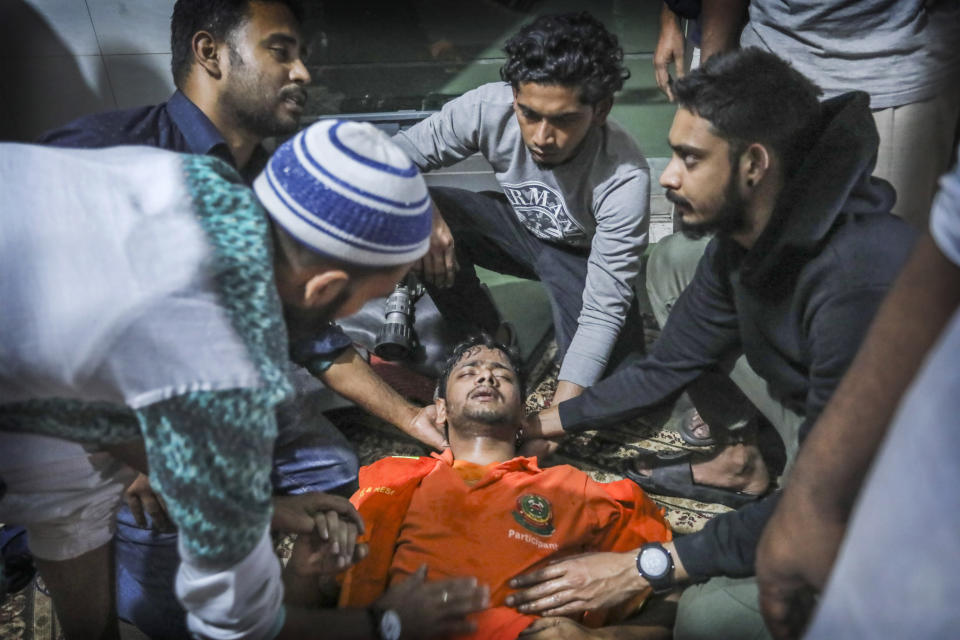 Locals help a Bangladeshi firefighter who lost consciousness briefly while trying to douse flames of a smoldering fire in a building in Dhaka, Bangladesh, Thursday, Feb. 21, 2019. The devastating fire raced through buildings in an old part of Bangladesh's capital and killed scores of people. (AP Photo/Zabed Hasnain Chowdhury)