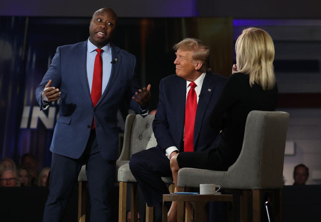 Tim Scott talks during a town hall event with Donald Trump looking on