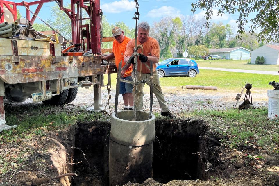 Well-repair company owner Lynn Rosenquist (in back) and his brother, Lanny, attach the end of a cable from their crane to an old concrete casing to remove it from a well near Fort Dodge, Iowa.