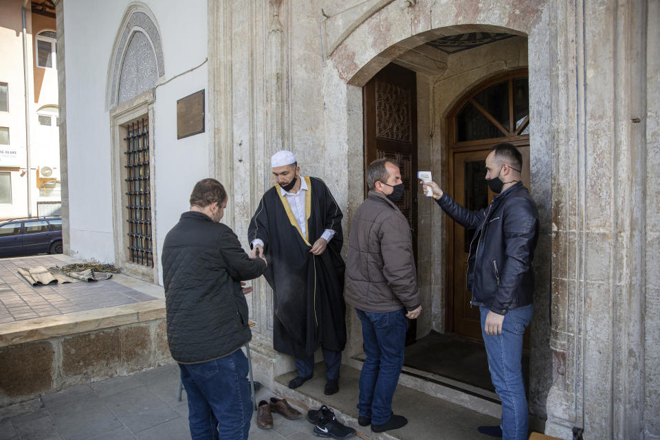 The Imam of the Grand Mosque Sami Fetahu, second left, disinfects the hands of a limited number of Muslim faithfuls attending the Friday prayer in coordination with latest government Covid-19 measures, in Kosovo's capital Pristina on Friday, April 9, 2021. The coronavirus pandemic is imposing a different way of fasting and respect of other religious rights for the Muslim faithful in Kosovo. (AP Photo/ Visar Kryeziu)