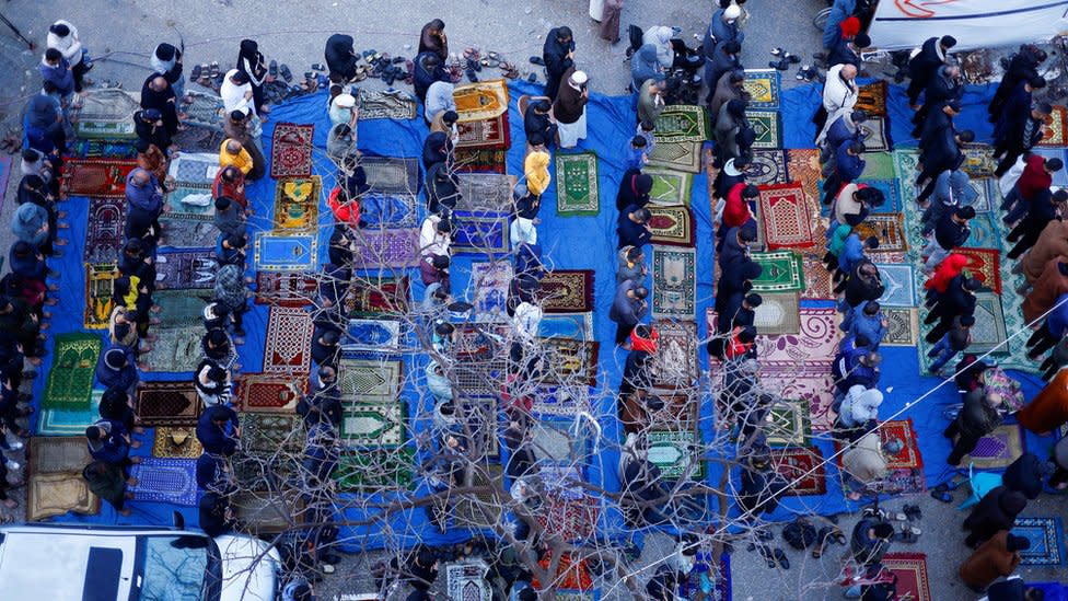 Aerial view of people praying in front of prayer rug in Rafah, the Gaza Strip.