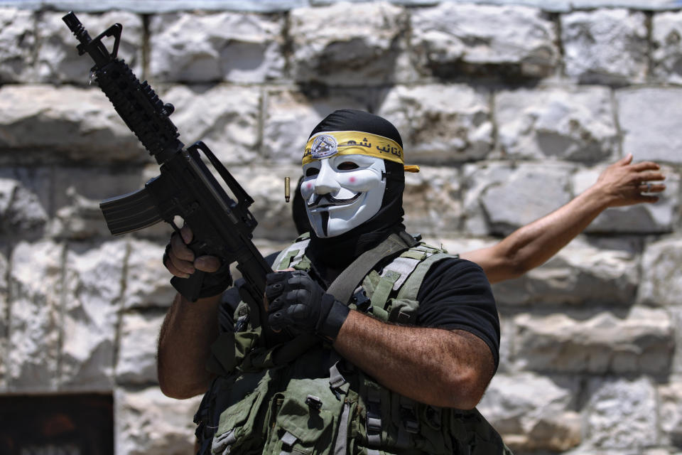 A masked Palestinian protester shoots in the air following the funeral of Mohammed al-Alami, 12, in the village of Beit Ummar, near the West Bank city of Hebron, Thursday, July 29, 2021. Villagers say the boy was fatally shot by Israeli troops while traveling with his father in a car. The Israeli military has launched an investigation into the shooting. (AP Photo/Majdi Mohammed)