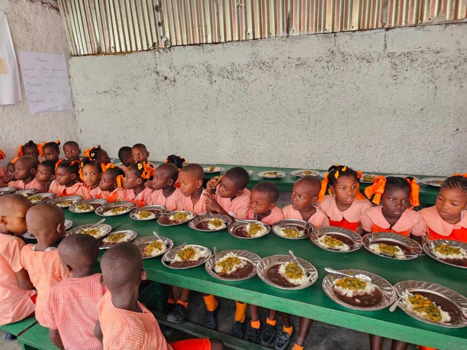 Alumnos de la Escuela Elim de Jérémie se preparan para comer una comida caliente gratuita preparada con cultivos locales. El programa de alimentación escolar cuenta con el apoyo del Programa Mundial de Alimentos de la ONU, cuya nueva directora ejecutiva, Cindy McCain, visitó la escuela el lunes 19 de junio de 2023.