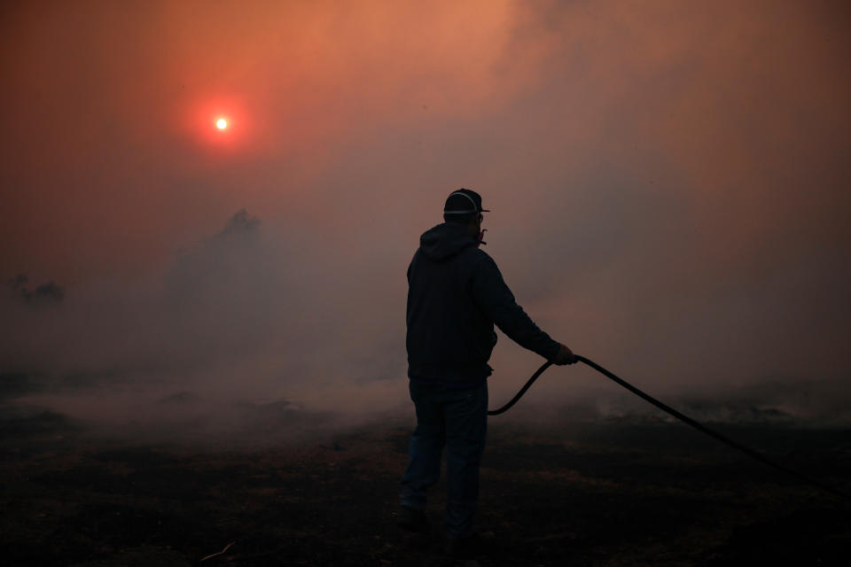 A worker wets the ground in a ranch as the Easy Fire spreads in Simi Valley, North of Los Angeles, Calif., on Oct. 30, 2019. (Photo: Etienne Laurent/EPA-EFE/Shutterstock)