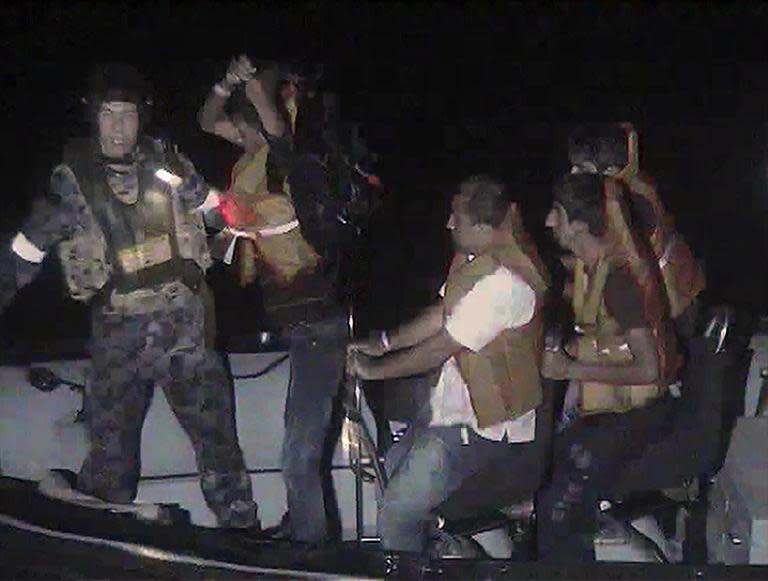 A member of the Australian navy (L) assists rescued asylum-seekers as they transfer to an Indonesian search and rescue boat in the waters off western Java on September 26, 2013