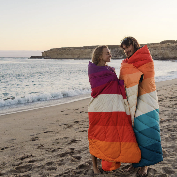 two models wrapped up in blankets on a beach